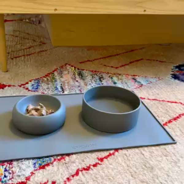 Two slate grey Houndstone silicone bowls on a matching feeding mat over a colorful rug
